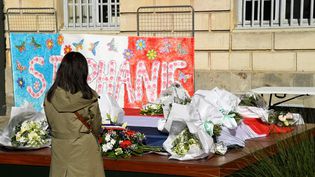 Une femme se recueille, le 26 avril 2021, devant un message et des fleurs en hommage à&nbsp;Stéphanie Monfermé, la fonctionnaire de police tuée lors d'une attaque au couteau au commissariat de Rambouillet (Yvelines). (BERTRAND GUAY / AFP)